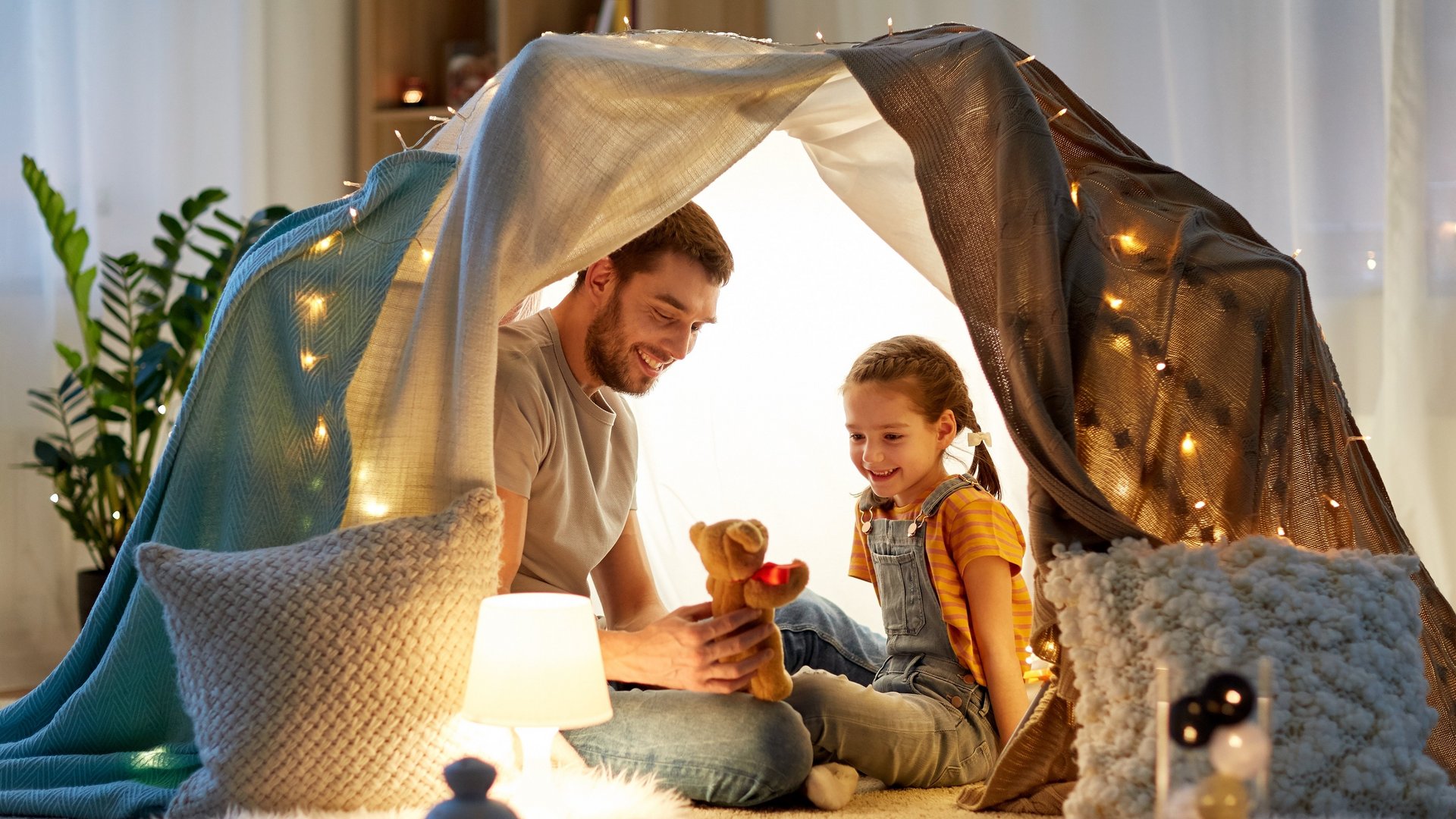 Vater und Tochter spielen im beleuchteten Zelt im Kinderzimmer