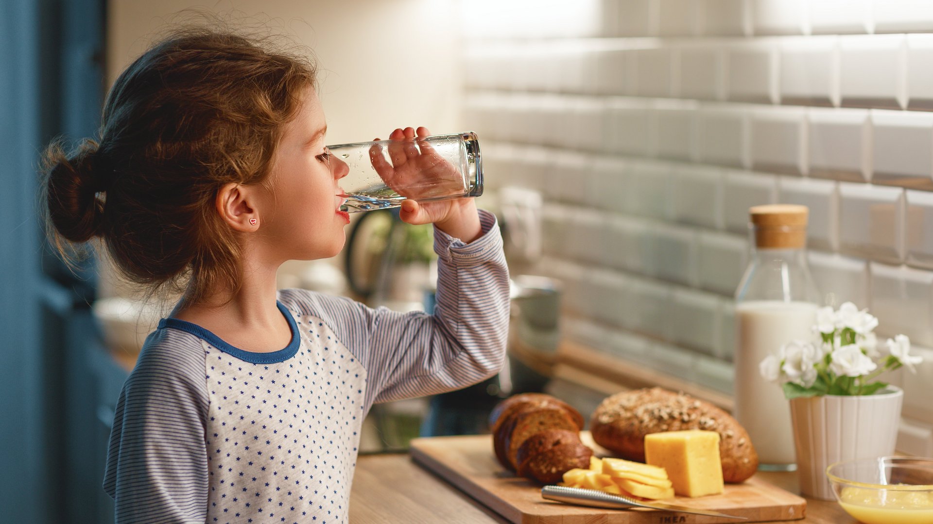 Kind trinkt Wasser aus einem Glas in der Küche Kind trinkt Wasser in der Küche zum Frühstück