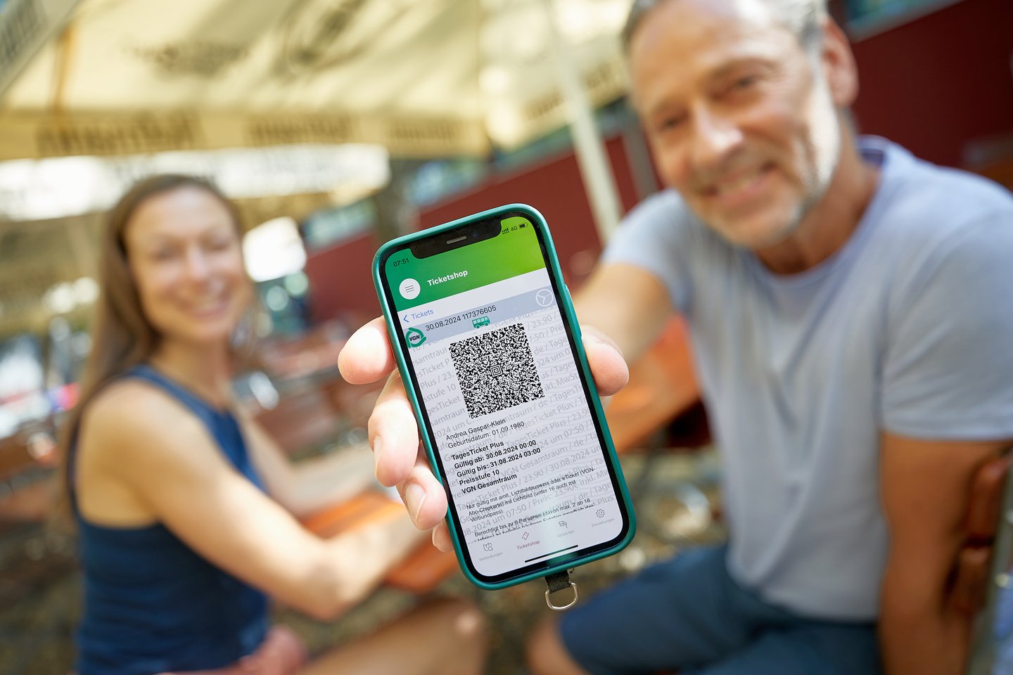 Mann halt Smartphone mit VGN App. Frau ist im Hintergrund