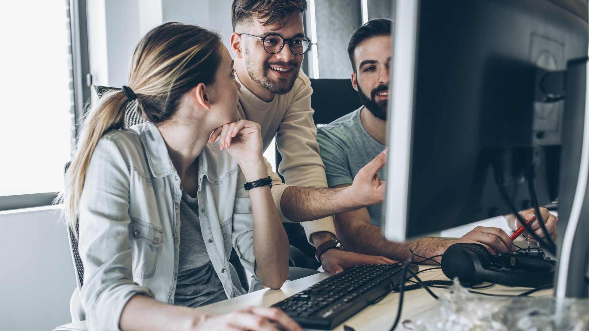 Drei Kollegen schauen auf einen Bildschirm Drei Kollegen schauen auf einen Bildschirm