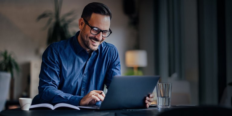 Mann sitzt mit Notebook am Schreibtisch