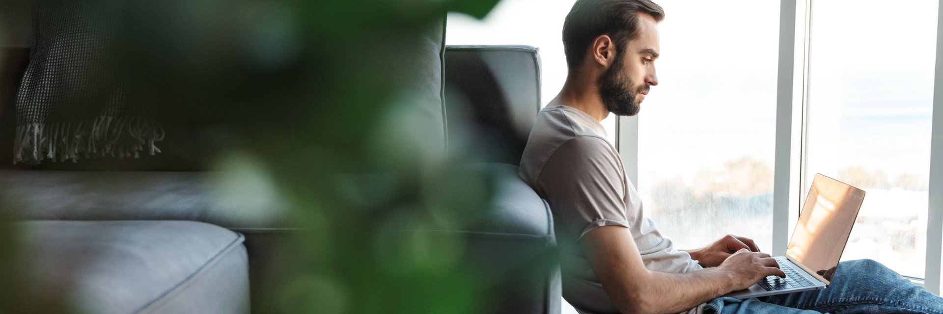 Mann sitzt mit Laptop am Boden